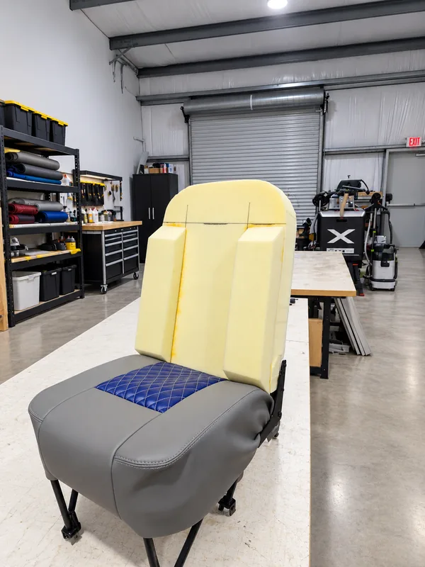 A seat in the shop: the bottom is covered in grey leather with a blue quilted insert, and new foam cores are fitted to the back